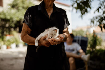 Midsection on woman holding cat outdoors