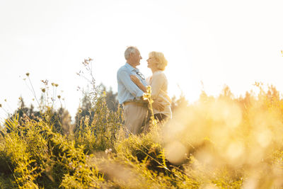 Man and woman, both seniors, embracing each other on a meadow