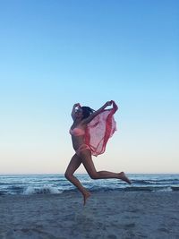 Woman with umbrella on beach against clear sky