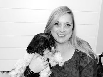 Portrait of smiling woman holding dog at home