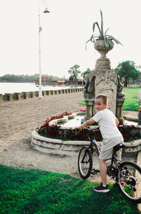 Boy with bicycle standing by plants