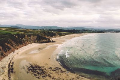 Scenic view of beach against cloudy sky