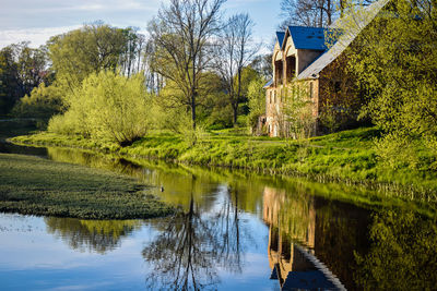 Scenic view of lake by house and trees by plants