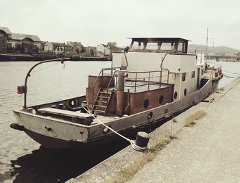 Abandoned boat moored at harbor against sky