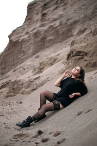 Portrait of woman sitting on sand at desert