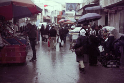 People walking on wet street in city during rainy season