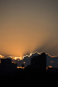 Illuminated city against sky at sunset