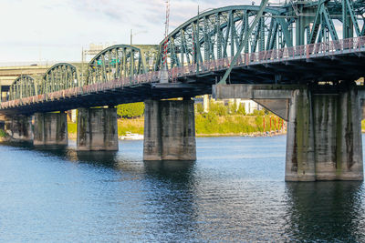 Bridge over river in city against sky