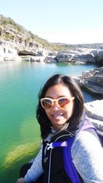 Portrait of smiling young woman by sea against clear sky