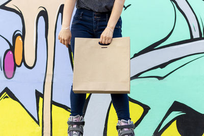 Low section of woman standing against graffiti wall