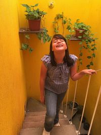 Young woman smiling while standing against plants