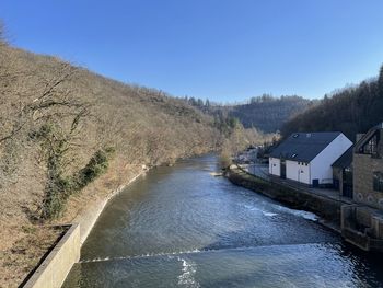 Scenic view of river amidst buildings against clear blue sky