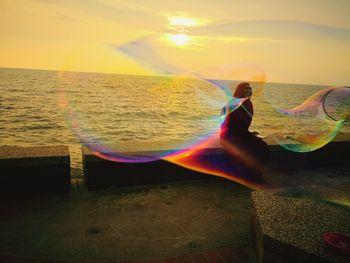 Scenic view of rainbow over sea at sunset