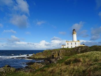 Lighthouse by sea against sky