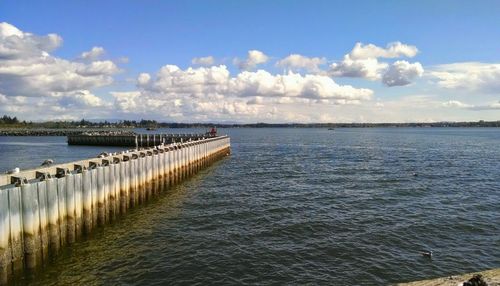 Pier on sea against cloudy sky