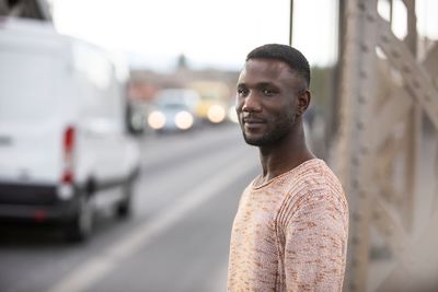 Portrait of young man standing on road in city