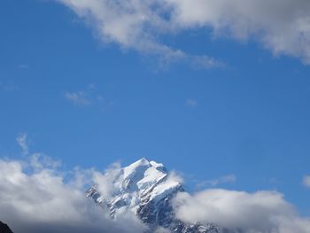 Low angle view of snow mountains against blue sky