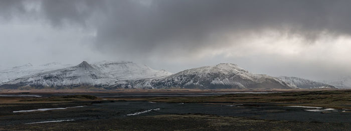 Scenic panoramic view of snow covered mountain range with ominous low hanging clouds