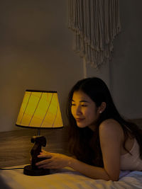 Young woman sitting on bed at home