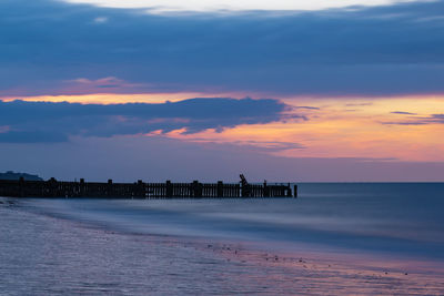 Silhouette people on beach against romantic sky at sunset