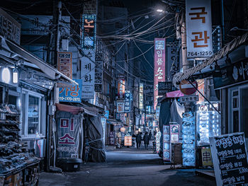 Illuminated street amidst buildings in city at night