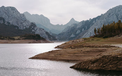 Scenic view of river by mountains against sky