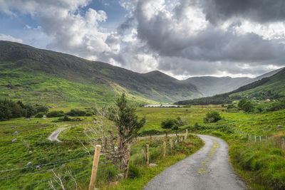 Road amidst green landscape against sky