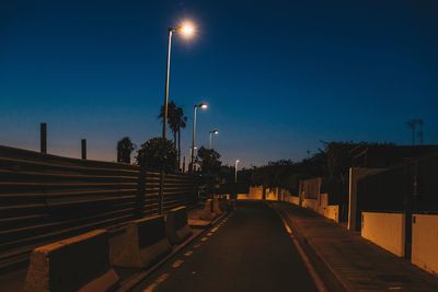 Illuminated street lights against sky at dusk