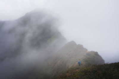 Rear view of hiker on mountain during foggy weather