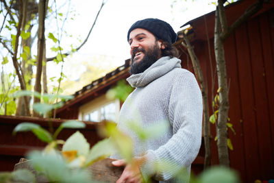 Young man looking away while standing outdoors