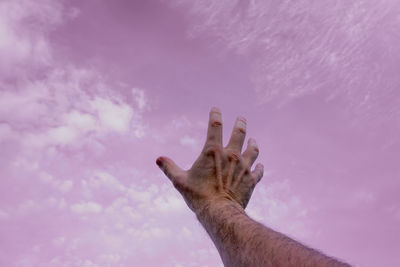 Cropped hand against sky