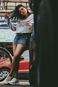 Full length of woman standing against car