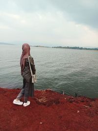 Rear view of girl in headscarf looking at sea