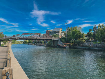 Bridge over river against sky in city