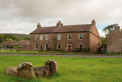 Old building on field against cloudy sky