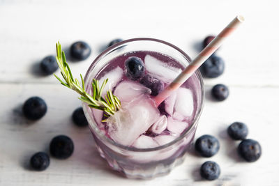 Soda water with ice and fresh berries, garnished with a sprig of rosemary. summer drinks
