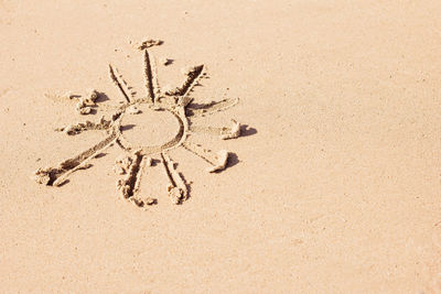 The sun is painted on the sand, rest and summer, warm season, beach season, sun protection