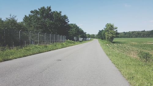 Road by trees against sky