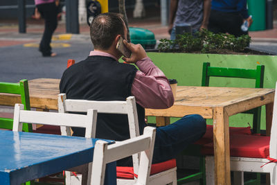 Rear view of man sitting on bench