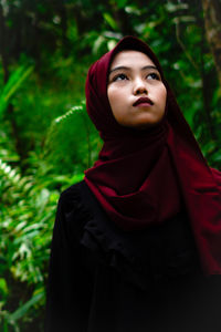 Portrait of young woman wearing hijab against plants