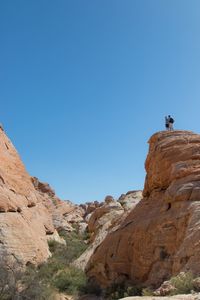 Low angle view of people on rock against sky