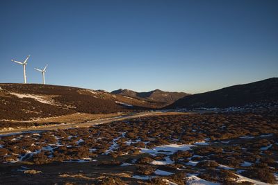 Wind turbines on landscape against clear blue sky