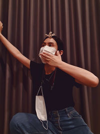 Asian woman wearing a surgical mask, sitting on the floor and covering her mouth