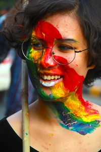  smiling young woman with paint on her face wearing eyeglasses outdoors