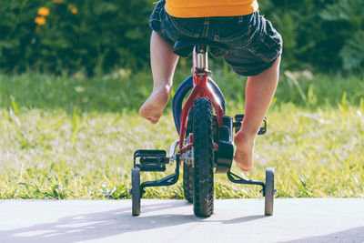 Low section of boy riding bicycle on road