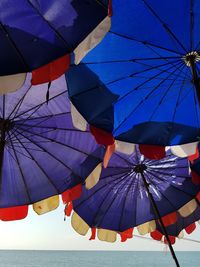 Low angle view of umbrellas on beach against blue sky