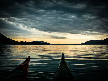 Boats in sea against cloudy sky