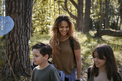 Portrait of smiling girl on tree trunk against trees