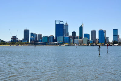 City at waterfront against blue sky