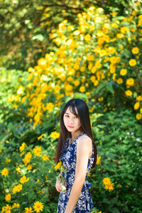 Full length of woman standing on yellow flowering plants